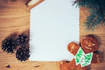 Czysta kartka papieru na drewnianej podłodze z ołówkiem i ozdobami świątecznymi