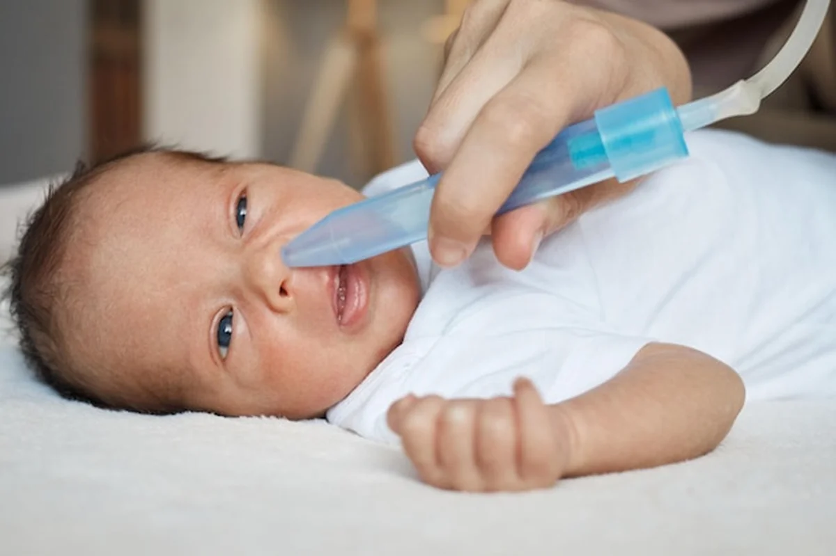 Matka czyści nos niemowlaka aspiratorem nosowym