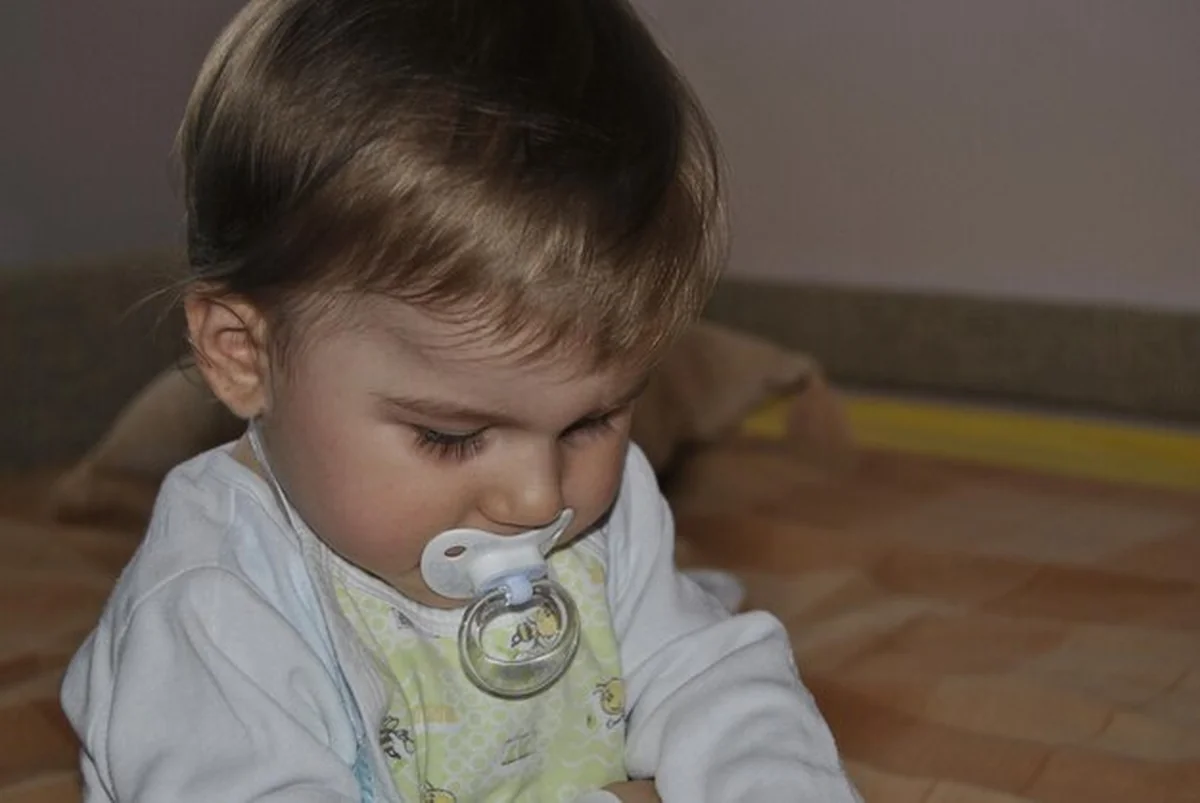 Chłopiec z smoczkiem na łóżku w domu