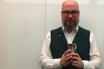 Dojrzały mężczyzna trzymający telefon komórkowy przy ścianie