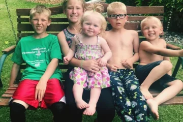 Rodzeństwo siedzące na drewnianej huśtawce