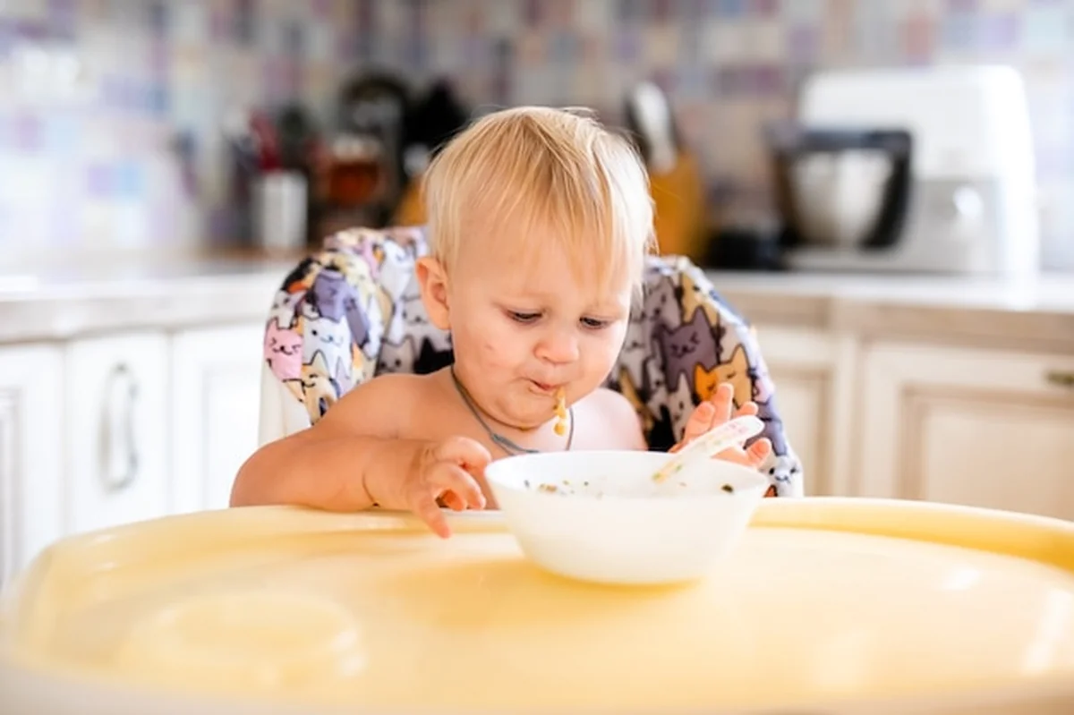 Dziecko w foteliku je zupę, potem warzywa łyżką