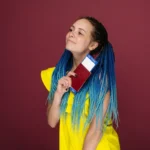 Młoda kobieta w żółtej sukience z paszportem i biletami lotniczymi