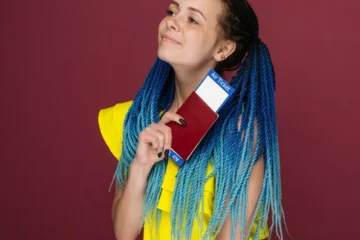 Młoda kobieta w żółtej sukience z paszportem i biletami lotniczymi