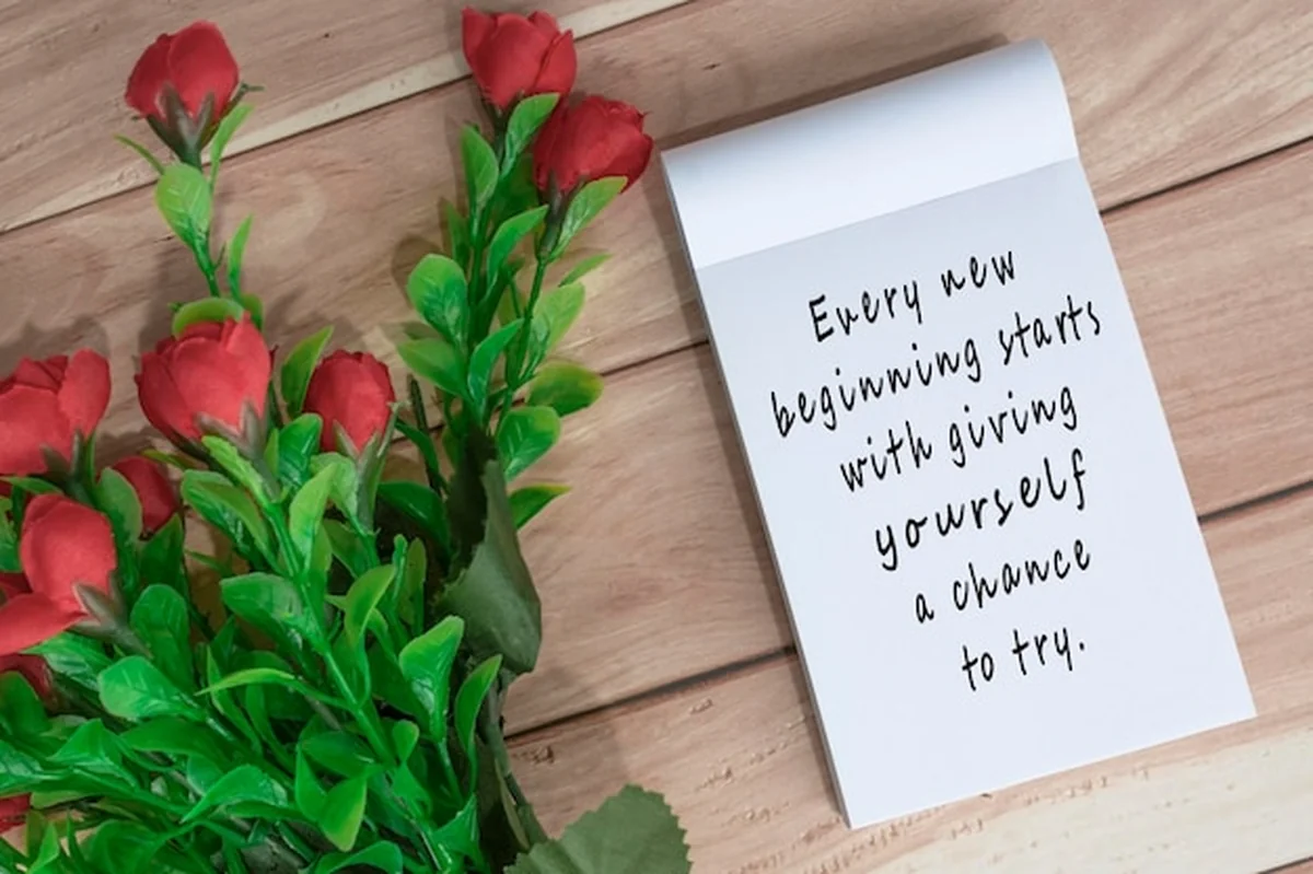 Motywacyjny cytat na notatniku z kwiatami na biurku