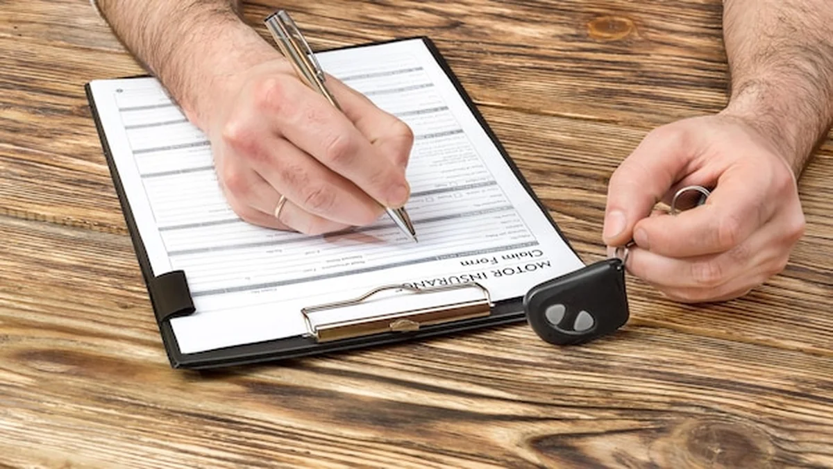 Mężczyzna wypełnia formularz ubezpieczenia samochodu