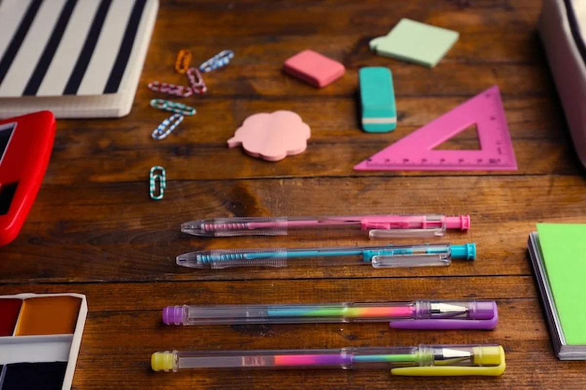 Zestaw szkolny na drewnianym tle z notatnikami, długopisami i naklejkami