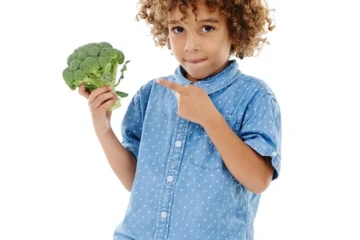 Portret młodego dziecka z brokułem na białym tle