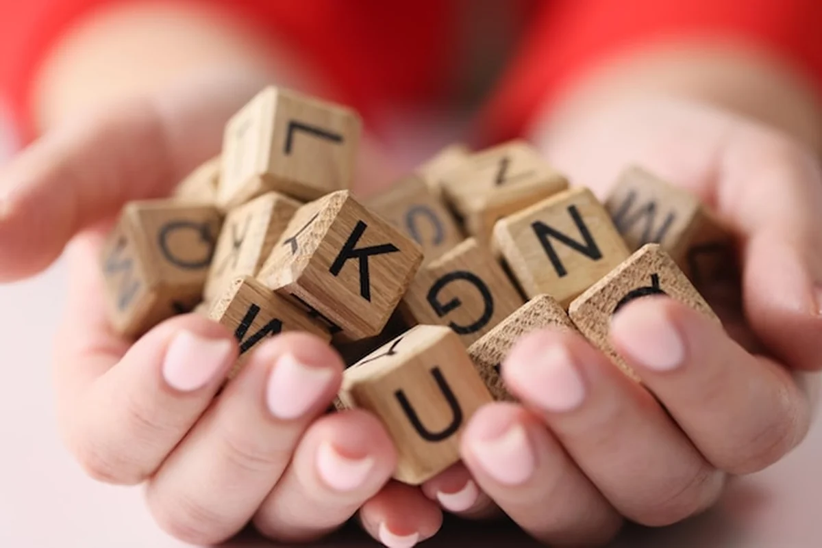 Ręce kobiety trzymają sterty drewnianych kostek z literami