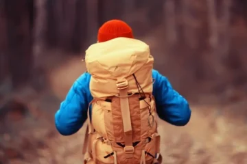 Mężczyzna z plecakiem w lesie, jesienny krajobraz