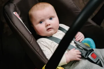 Mała dziewczynka bawi się zabawkami, niemowlę w foteliku samochodowym, uśmiech