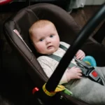 Dziewczynka i niemowlę w foteliku samochodowym, bawią się zabawkami, uśmiechają się