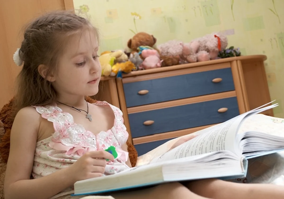 Mała dziewczynka czytająca książkę na łóżku