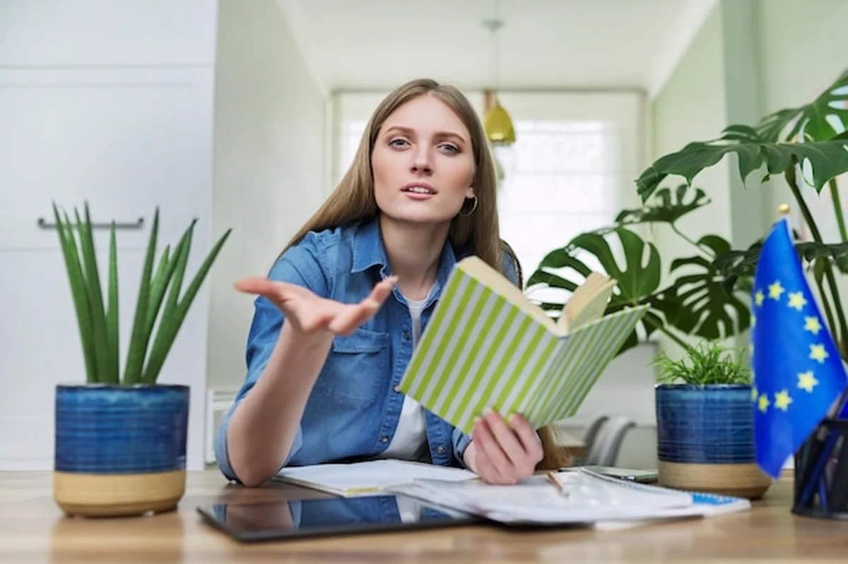 Studentka uniwersytetu z książką patrząca na kamerę online